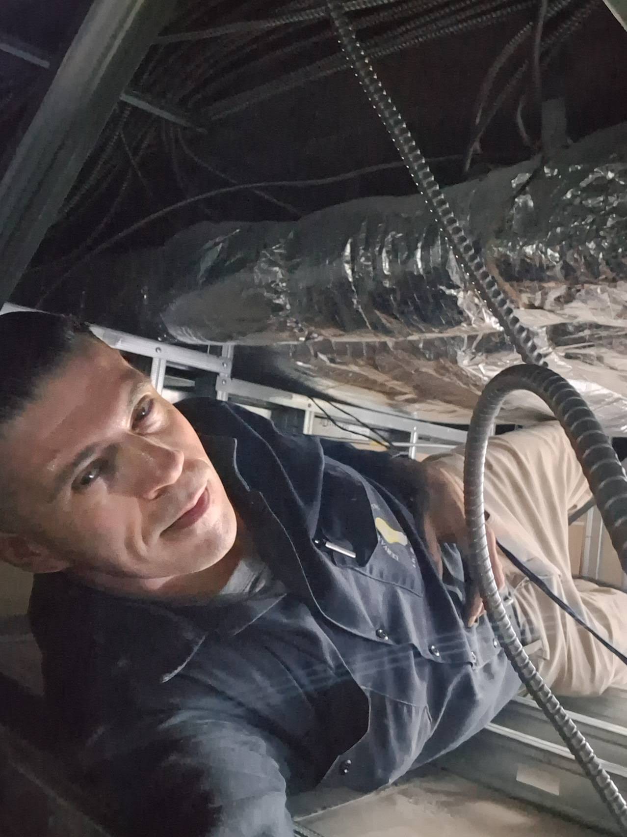 Electrician running conduit through a tight ceiling space